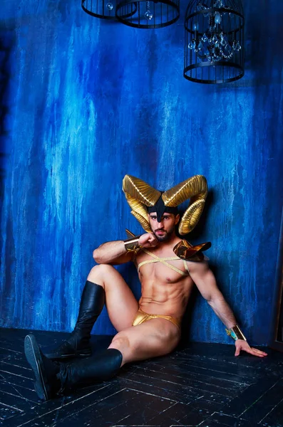  stüdyoda büyük altın boynuzlarıyla sahne kostüm giyen kaslı yakışıklı adam