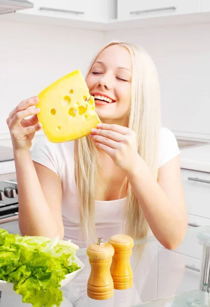 キッチンで家庭でチーズを食べて若いブロンド美人 — ストック写真