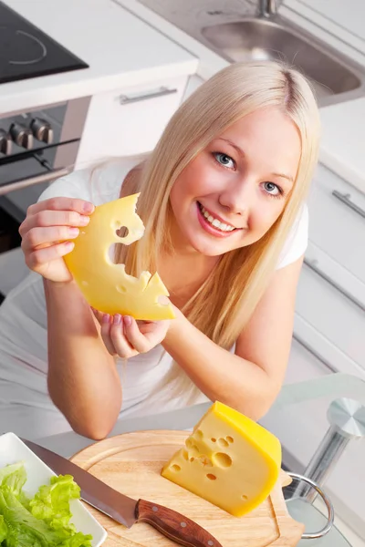 在厨房吃奶酪的美丽的年轻妇女 — 图库照片