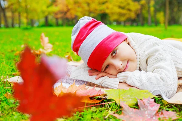 快乐可爱男孩在秋天公园以绿色草和黄色叶子 — 图库照片