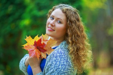 Sonbahar parkta uzun kıvırcık saçlı güzel genç plussize modeli