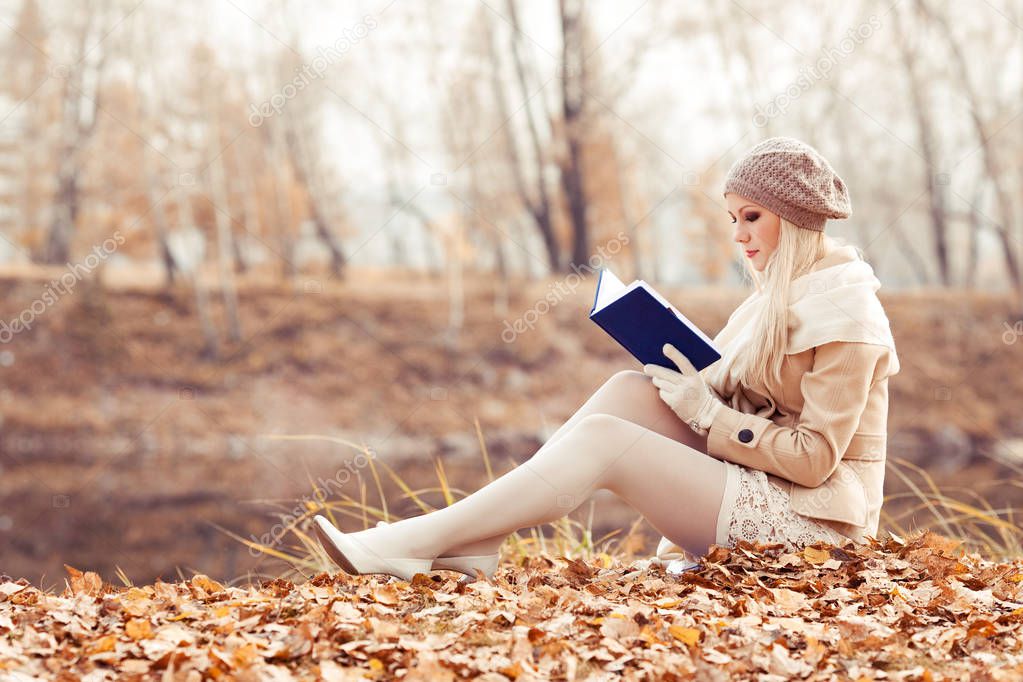 happy blond woman reading in the autumn park