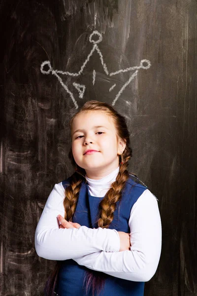 可爱的小女生对黑板 在她的头上拔冠 — 图库照片