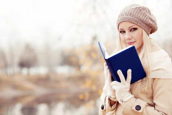 在秋季公园读一本书的快乐金发女郎 — 图库照片
