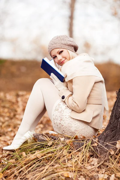 在秋季公园读一本书的快乐金发女郎 — 图库照片