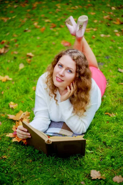 美丽的年轻 Plussize 妇女读一本书在秋天公园 — 图库照片