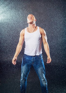 Stüdyo photoshoot yağmur altında ıslak giysileri ile çekici bir genç adam
