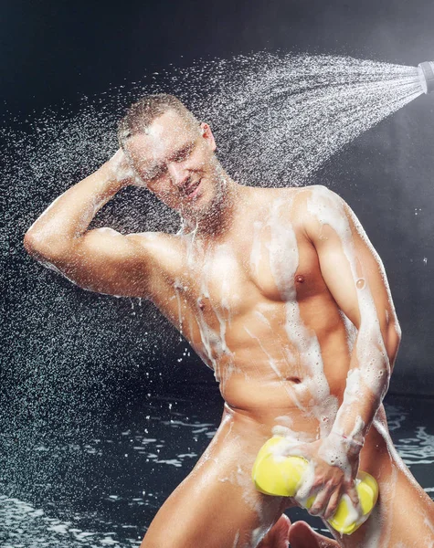 一个英俊的肌肉迷人的年轻人洗澡时带海绵和沐浴露 — 图库照片