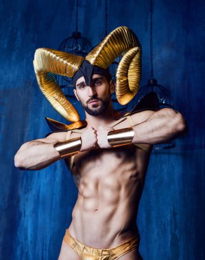 stüdyoda büyük altın boynuzlarıyla sahne kostüm giyen kaslı yakışıklı adam