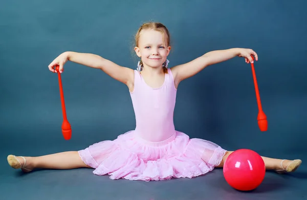 Flicka gymnast med en boll och klubbar — Stockfoto