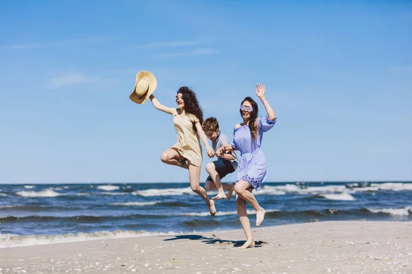 母亲和孩子们在海滩上跳得很高 家庭度假 — 图库照片