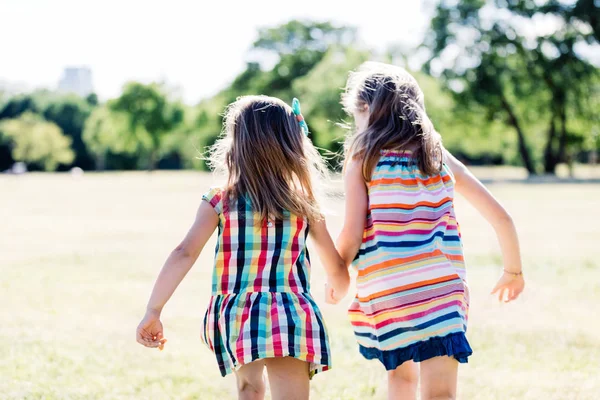 两个快乐的女孩穿着五颜六色的连衣裙在公园里奔跑 — 图库照片