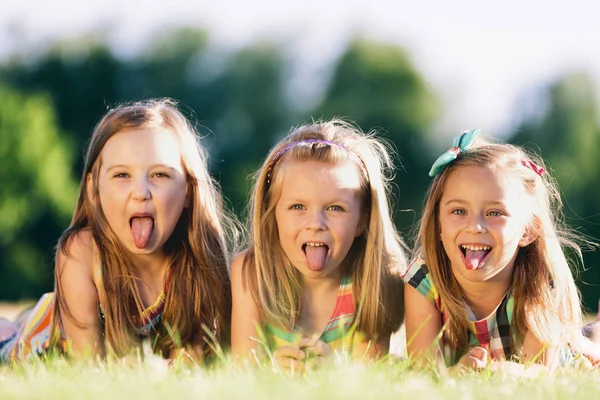 Três Meninas Colando Línguas Para Fora Deitadas Grama Parque Pequenos — Fotografia de Stock