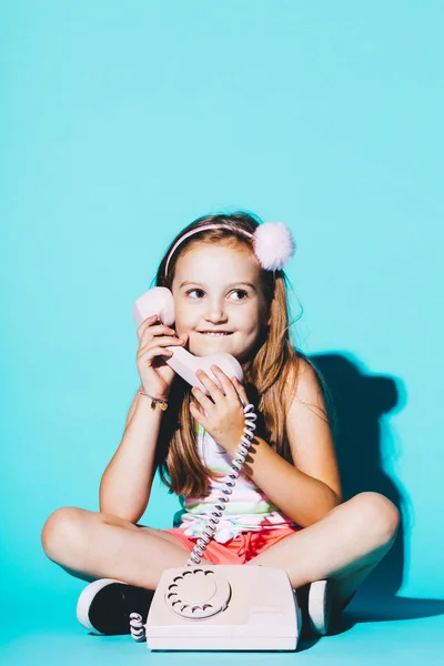 Κοριτσάκι Χρησιμοποιώντας Ροζ Αναλογικό Τηλέφωνο Κάθεται Στο Μπλε Φόντο Τηλεφωνική — Φωτογραφία Αρχείου