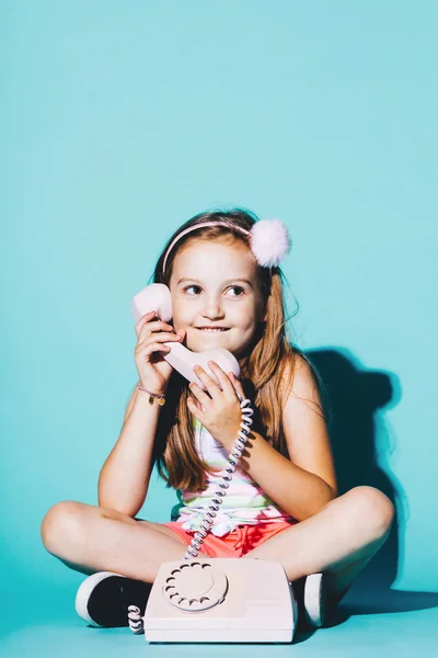 Κοριτσάκι Χρησιμοποιώντας Ροζ Αναλογικό Τηλέφωνο Κάθεται Στο Μπλε Φόντο Τηλεφωνική — Φωτογραφία Αρχείου