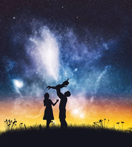 Happy parents with a baby on starry night sky. Joyful family, mother and father.