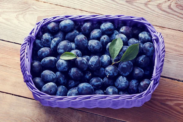 Purple Basket Delicious Raw Plums Green Leaves Wooden Background — Stock Photo, Image