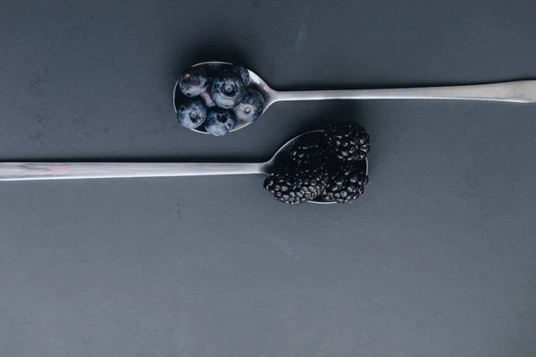 Böğürtlen ve karanlık bir adam üzerinde yaban mersini ile iki kaşık