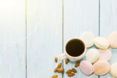 Bir fincan kahve ile bir açık mavi renkli badem fındık yanındaki üzerinde Marshmallows. Metin için yer