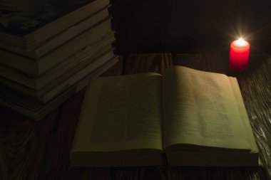 mum ve İncil'in geceleri ahşap arka plan üzerine bir kitap.