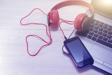 açık renkli laptop ve kırmızı ahşap kulaklıklar