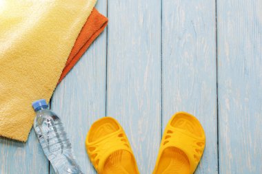 Şişe su ve parlak havlu, mavi zemin üzerine sarı şeyl.