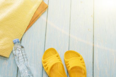 Şişe su ve parlak havlu, mavi zemin üzerine sarı şeyl.