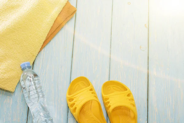 Şişe su ve parlak havlu, mavi zemin üzerine sarı şeyl.