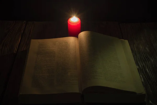 Vela e um livro da Bíblia sobre fundo de madeira à noite — Fotografia de Stock