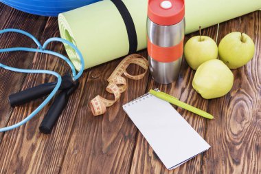 Yoga Mat ve su şişesi yakın çekim. Spor malzemeleri, üç yeşil elma ve bir ip atlama