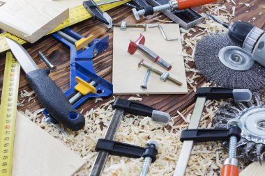 Kompozisyon farklı çalışma araçları keskiler, matkaplar, vidalar, bıçak ve cips üstünde okul sırası içinde Ahşap Atölyesi