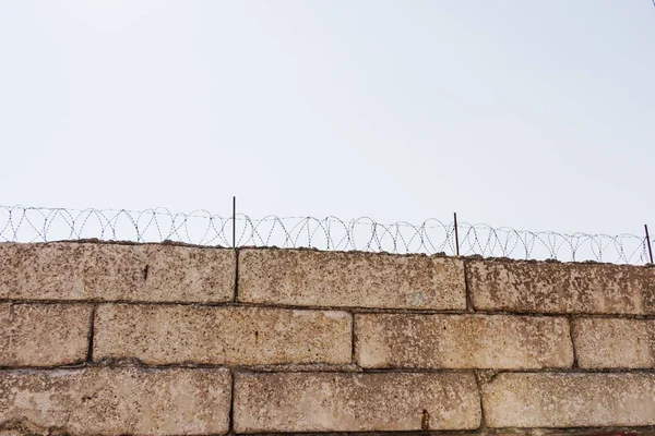 Mur avec fil barbelé sur fond de ciel bleu . — Photo