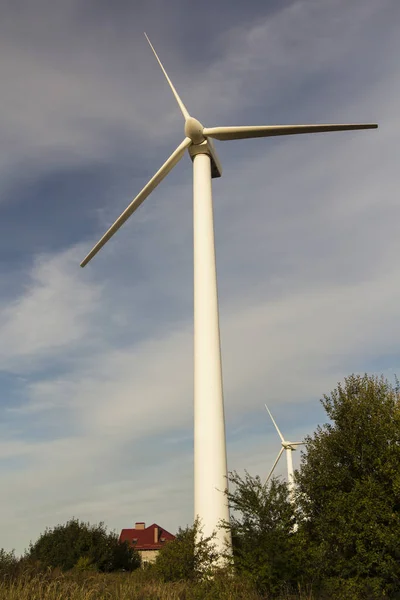 Windmill for electricity among the trees with the house