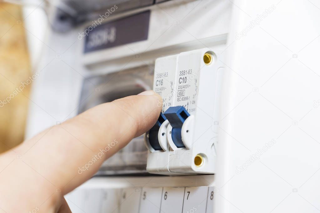 The hand points to a fuse in the power meter. The man disables the current fuses, the safety concept of the power suppression, and the protection of electrical devices.