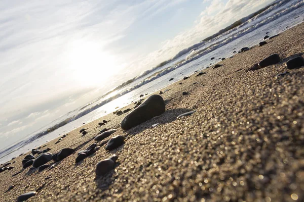 Increíble puesta de sol en la playa con horizonte infinito y piedras en primer plano . —  Fotos de Stock