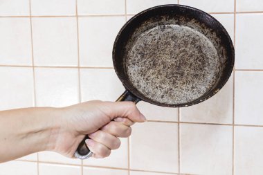 Eski moda dökme demir tavada bir kadının eli. Aile skandalı kavramı