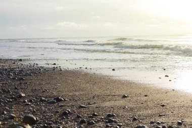 Muhteşem plaj günbatımı sonsuz ufuk ve taşlar ön planda.