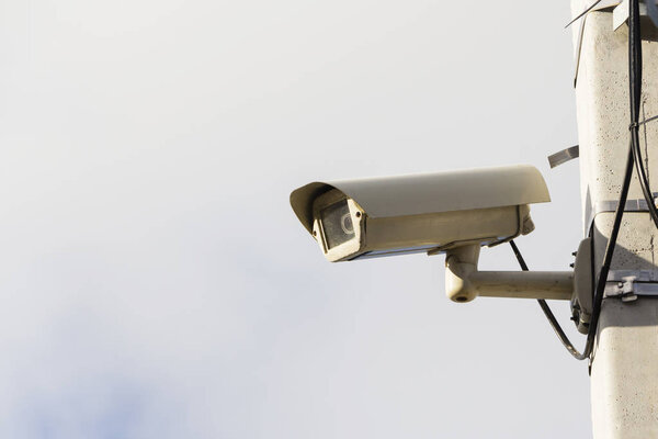 Modern compact video surveillance camera on support post in public areas on white background general plan.