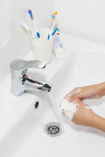 Hygiene concept. Washing hands with soap under the faucet with water.