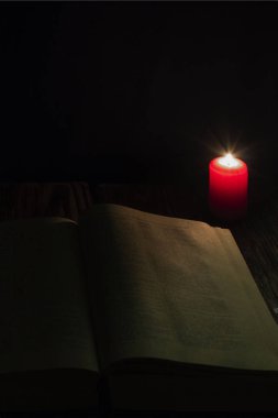 mum ve İncil'in geceleri ahşap arka plan üzerine bir kitap.