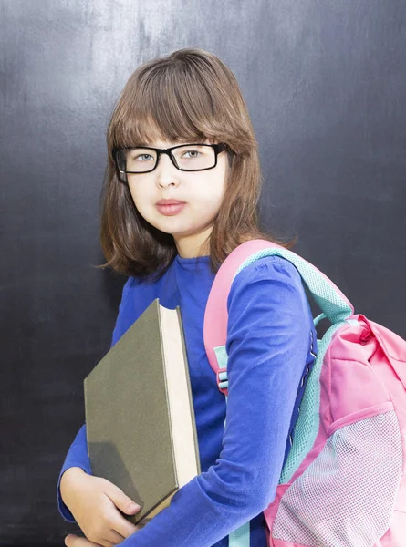 学校のコンセプトです バックパックと教室で黒い黒板で本の幸せな女子高生 — ストック写真