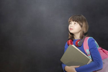 Geri okul kavramı. Sırt çantası ve sınıfta siyah kara tahta kitap ile mutlu kız öğrenci.