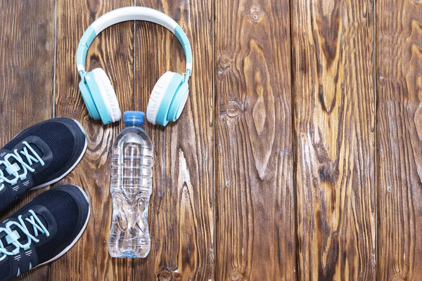 Equipamento desportivo. Sapatilhas, água e fones de ouvido em fundo de madeira — Fotografia de Stock