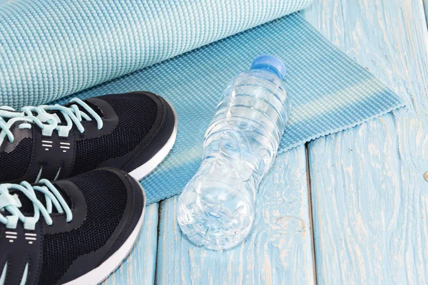 Estera de yoga, zapatos deportivos, botella de agua sobre fondo azul concepto de vida saludable, alimentación saludable, deportes y dieta — Foto de Stock