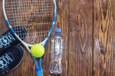 Tenis karanlık bir arka plan üzerinde. spor ayakkabı, roket, top, şişe suyu.