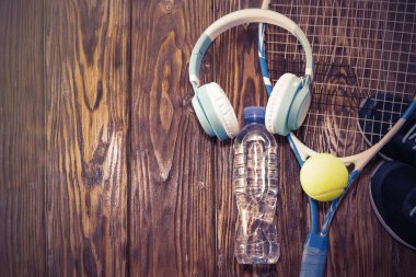 Tenis karanlık bir arka plan üzerinde. spor ayakkabı, roket, top, su şişesi, müzik kulaklık.