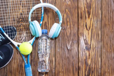 Tenis karanlık bir arka plan üzerinde. spor ayakkabı, roket, top, su şişesi, müzik kulaklık.