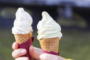 Kadının holding eritme dondurma waffle koni yaz ışık arka plan üzerinde elinde eller