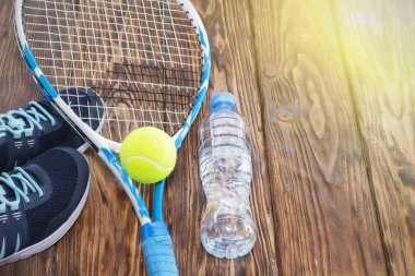 Tenis karanlık bir arka plan üzerinde. spor ayakkabı, roket, top, şişe suyu.
