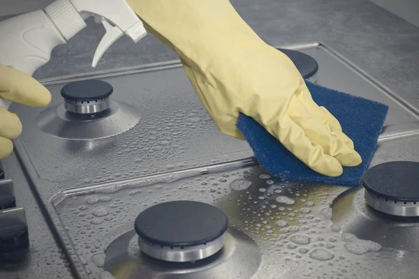 Hands in yellow gloves washing the gas stove. Stock Photo